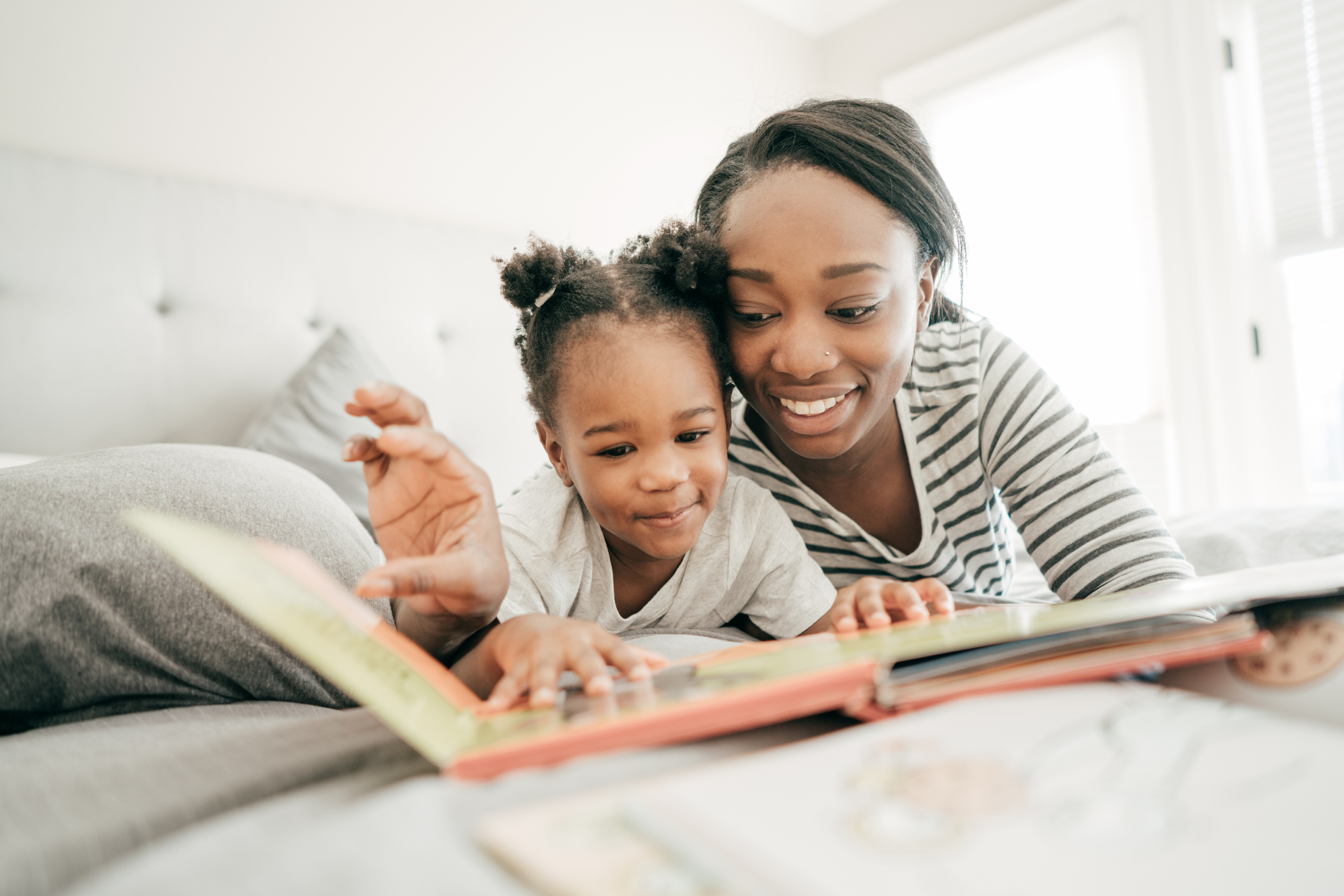 Mom and daughter reading fairy tales in bed.